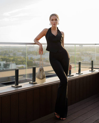 Woman in a black outfit standing on a balcony with a cityscape view