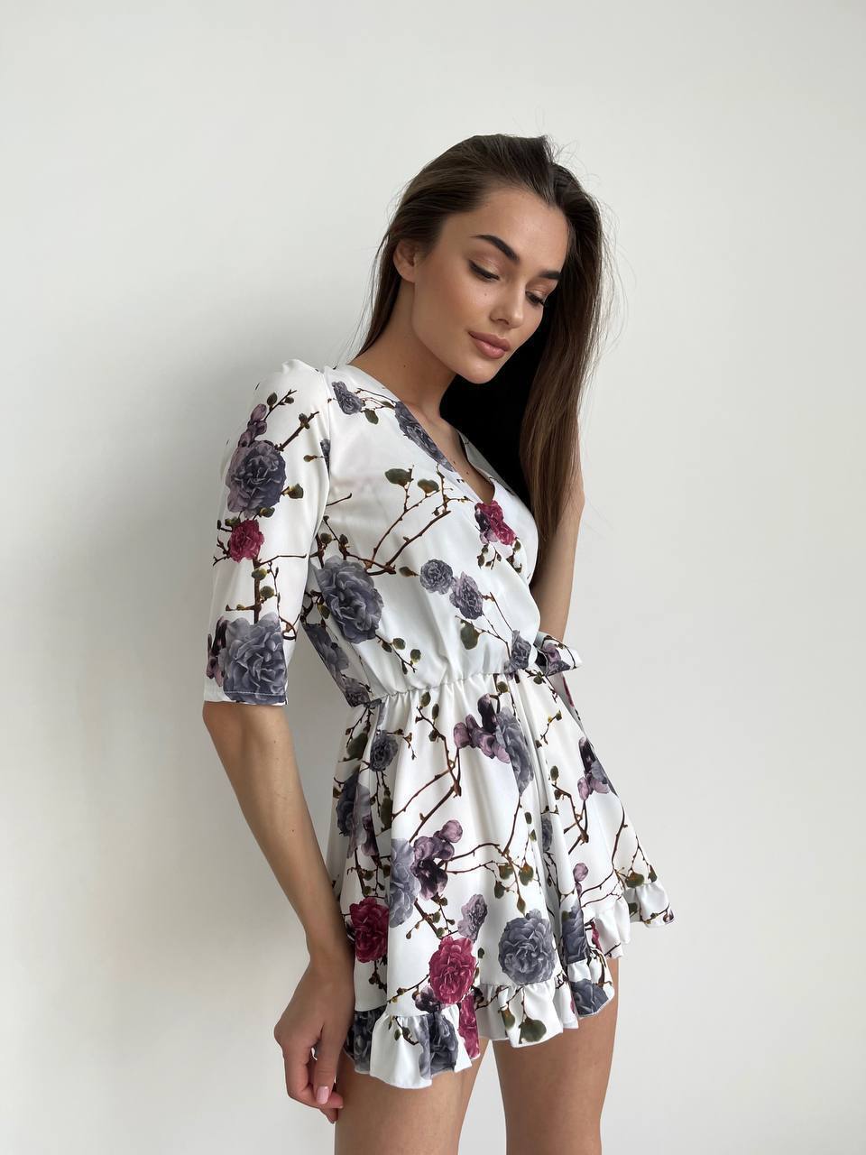 Woman wearing a floral dress against a plain background