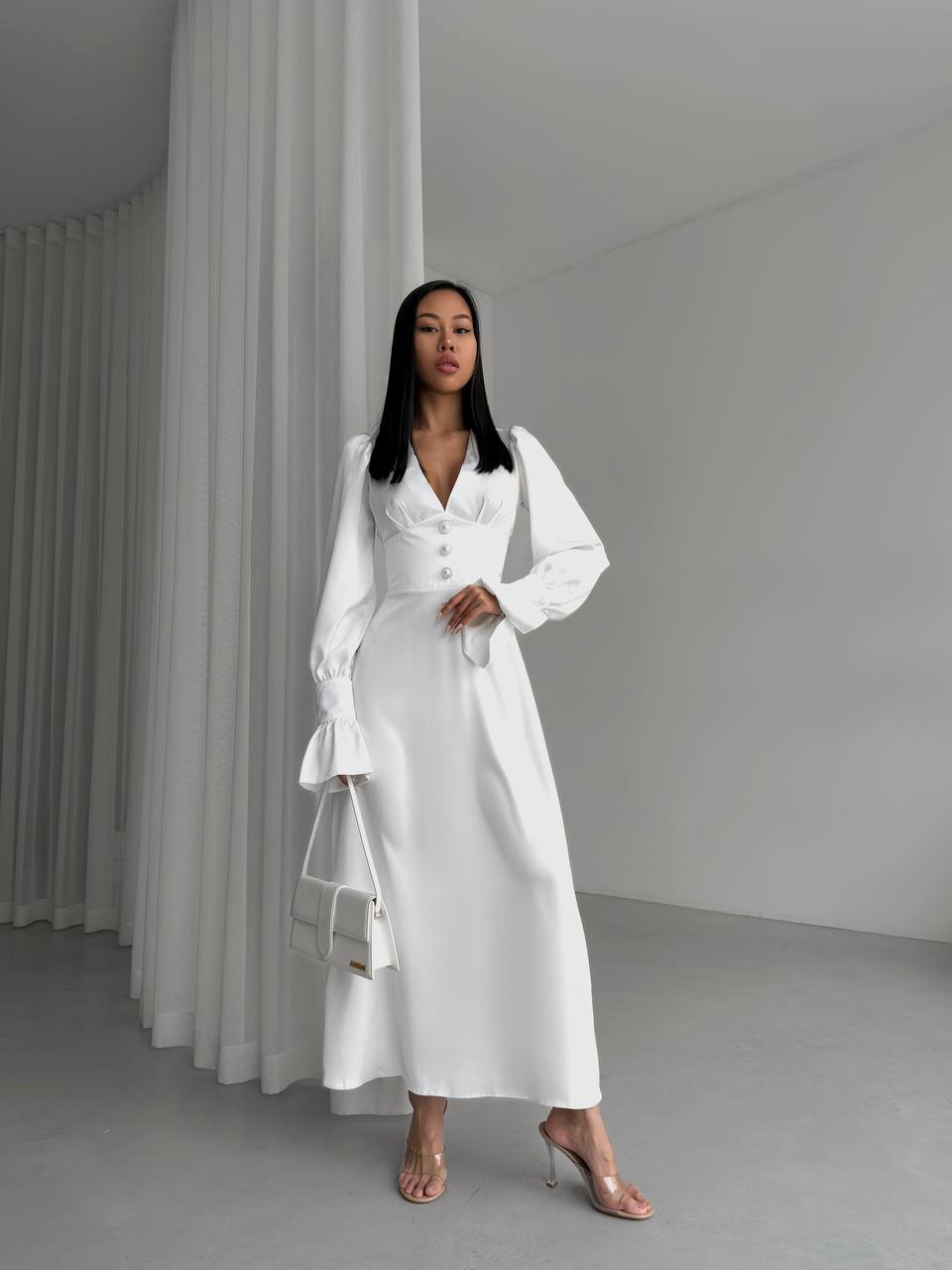 Woman in a white outfit standing against a plain background