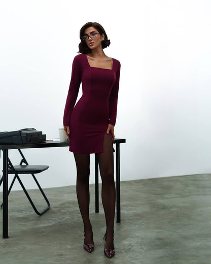 Woman wearing a burgundy dress standing in a minimalistic room.