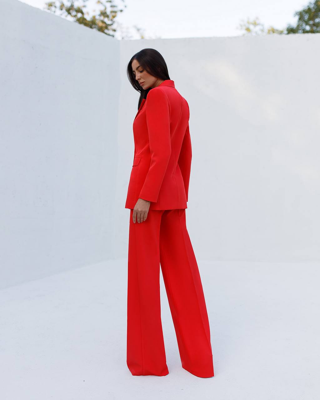 Person wearing a red suit standing against a white wall