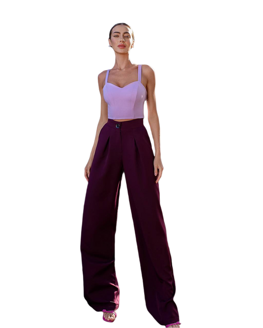Woman wearing a purple top and dark purple pants on a white background