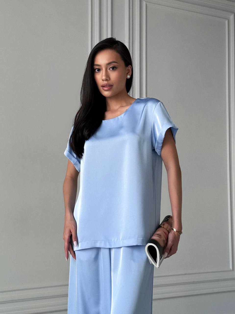 Woman wearing a light blue outfit against a gray wall
