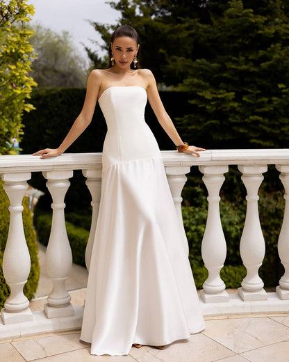 Woman in a white strapless gown standing on a balcony with greenery in the background