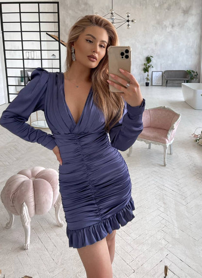 Woman taking a mirror selfie wearing a blue dress in a modern living room.