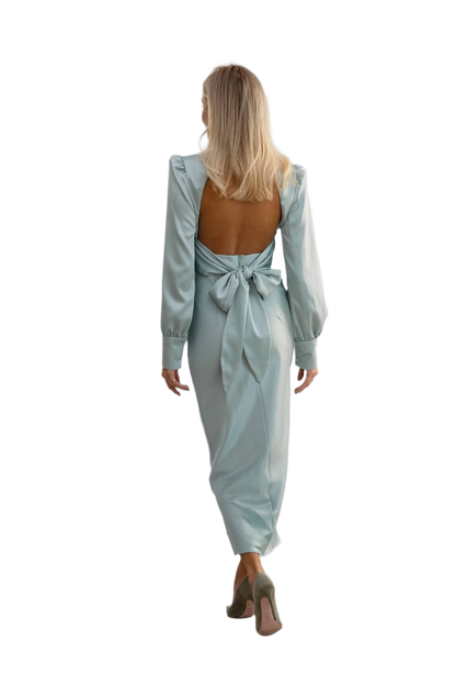 Woman wearing a light blue dress with a tie detail on a white background