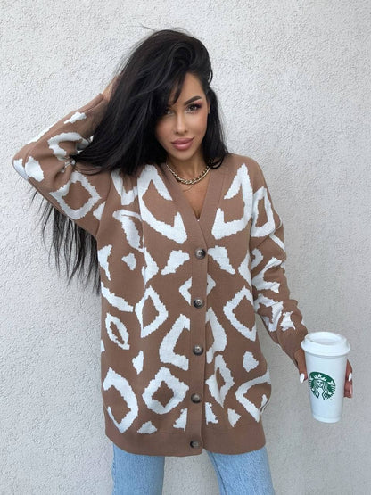 Woman wearing a patterned brown cardigan holding a Starbucks cup against a plain background