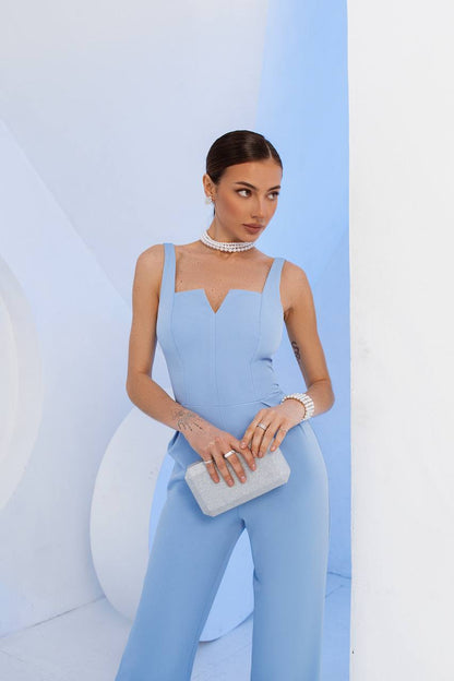 Woman in a light blue outfit holding a clutch against a white and blue background
