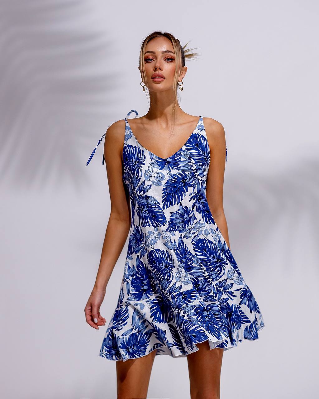 Woman wearing a blue and white floral dress against a plain background