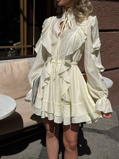 Woman wearing a white dress with ruffled details outdoors.