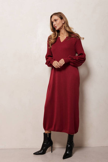 Woman wearing a burgundy dress with long sleeves against a white background