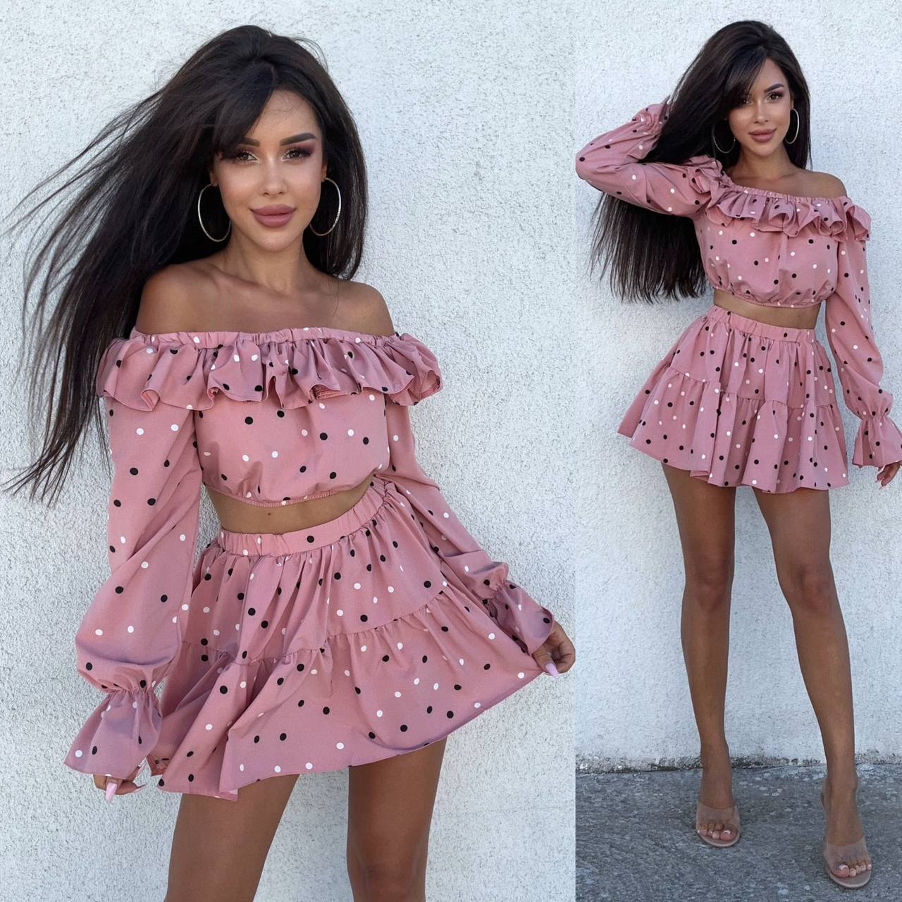 Woman wearing a pink polka dot outfit with long sleeves and a skirt against a white background.