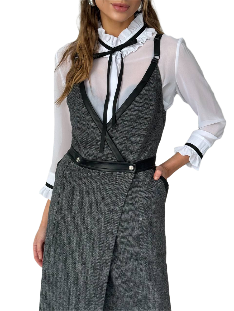 Woman wearing a gray vest over a white blouse with black accents on a white background