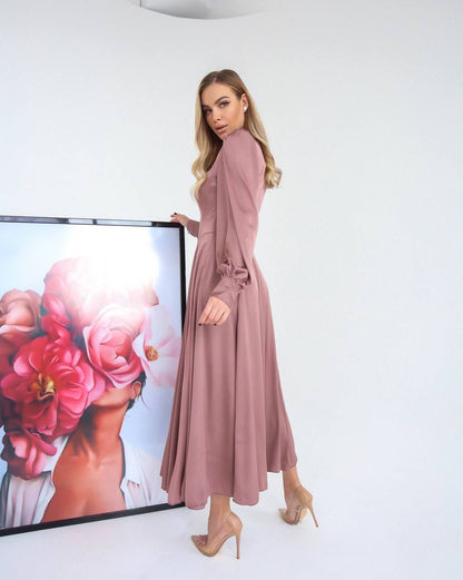 Woman in a pink dress standing next to a screen displaying floral images.