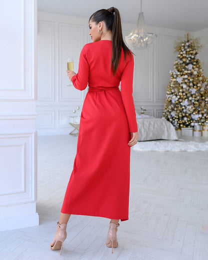 Woman in a red dress holding a glass in a room with a decorated Christmas tree.