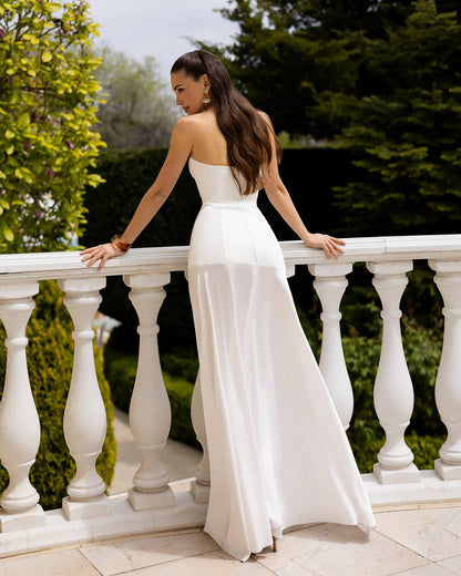 Woman in a white strapless gown standing on a balcony with greenery in the background