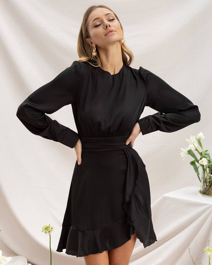 Woman wearing a black dress with long sleeves against a white background