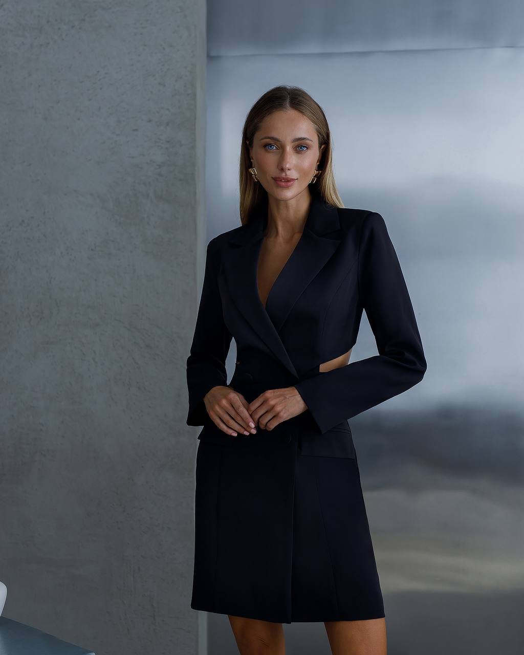 Woman wearing a black coat against a gray background