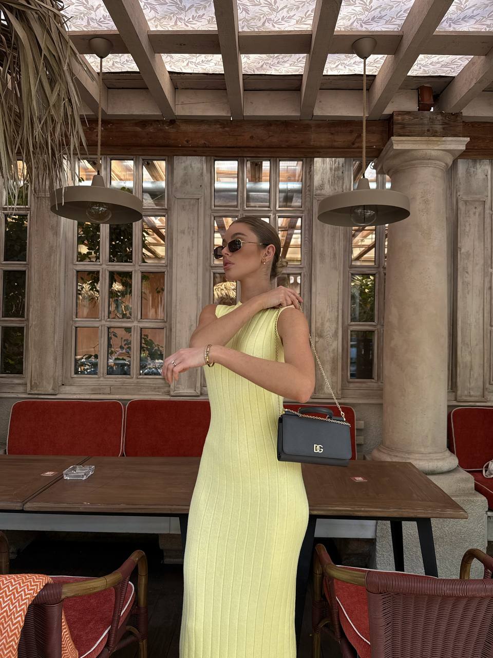 Woman in a yellow dress standing in an outdoor cafe setting