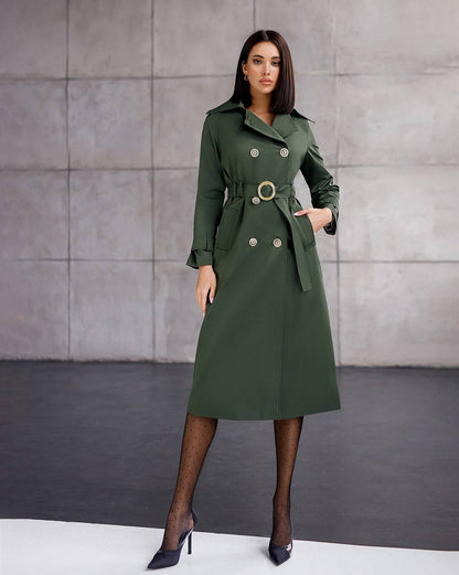 Woman wearing a green trench coat against a gray background