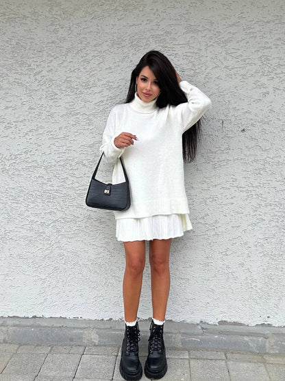 Woman in a white outfit with a black bag against a gray wall
