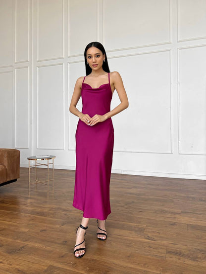 Woman in a pink dress standing in a room with wooden flooring and white paneled walls.