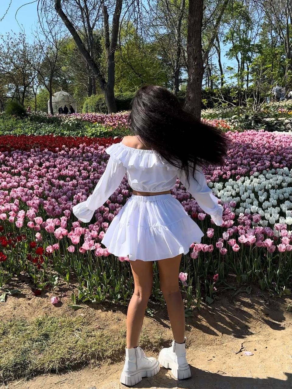Person in a white outfit standing in front of colorful tulip flowers