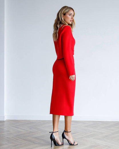 Woman wearing a red dress standing against a white wall.