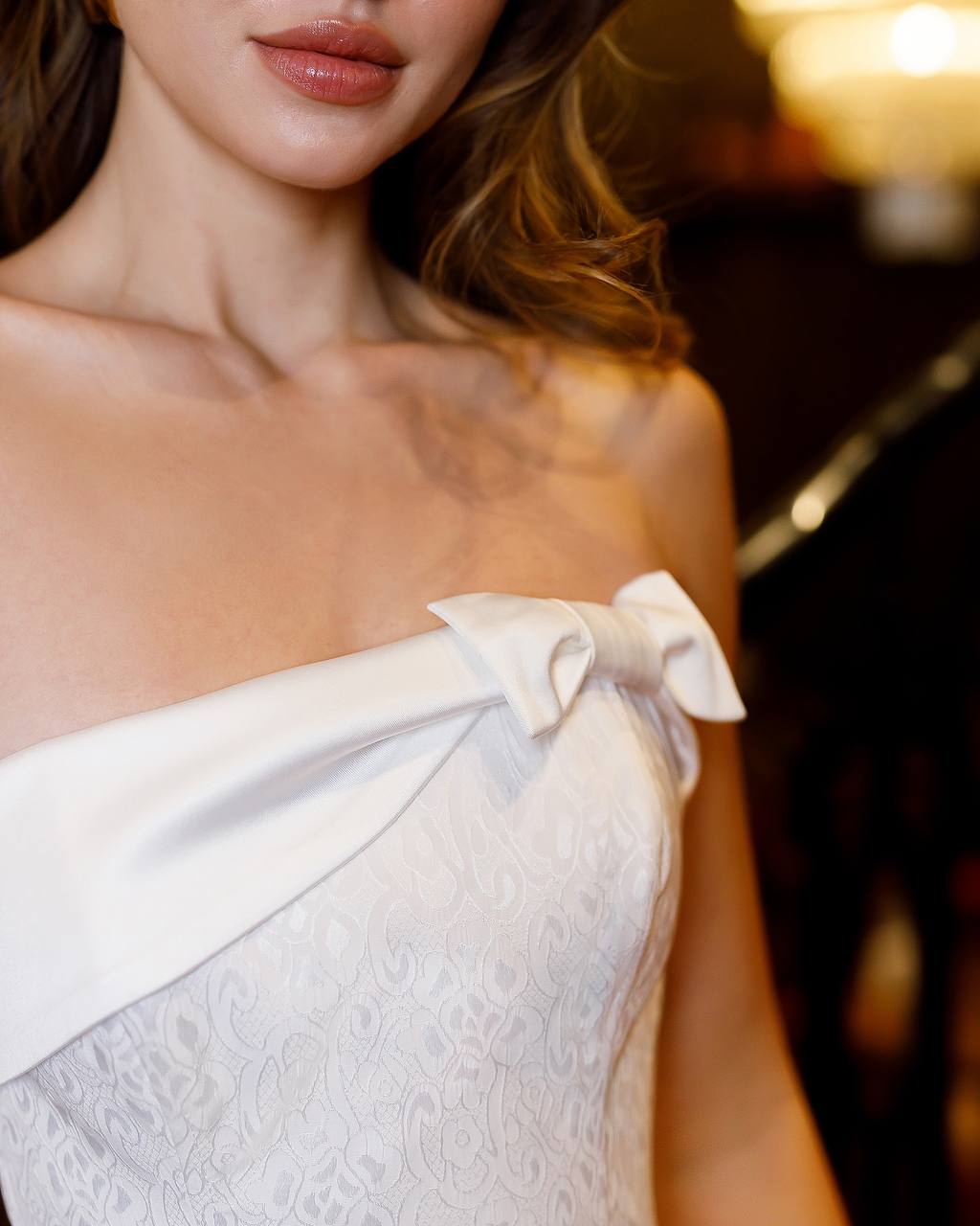 Close-up of a white strapless dress with a bow detail on a blurred background