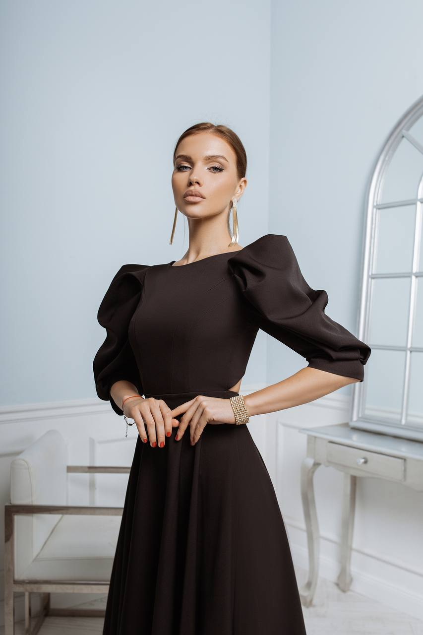 Woman wearing a black dress with puffed sleeves in an elegant room.
