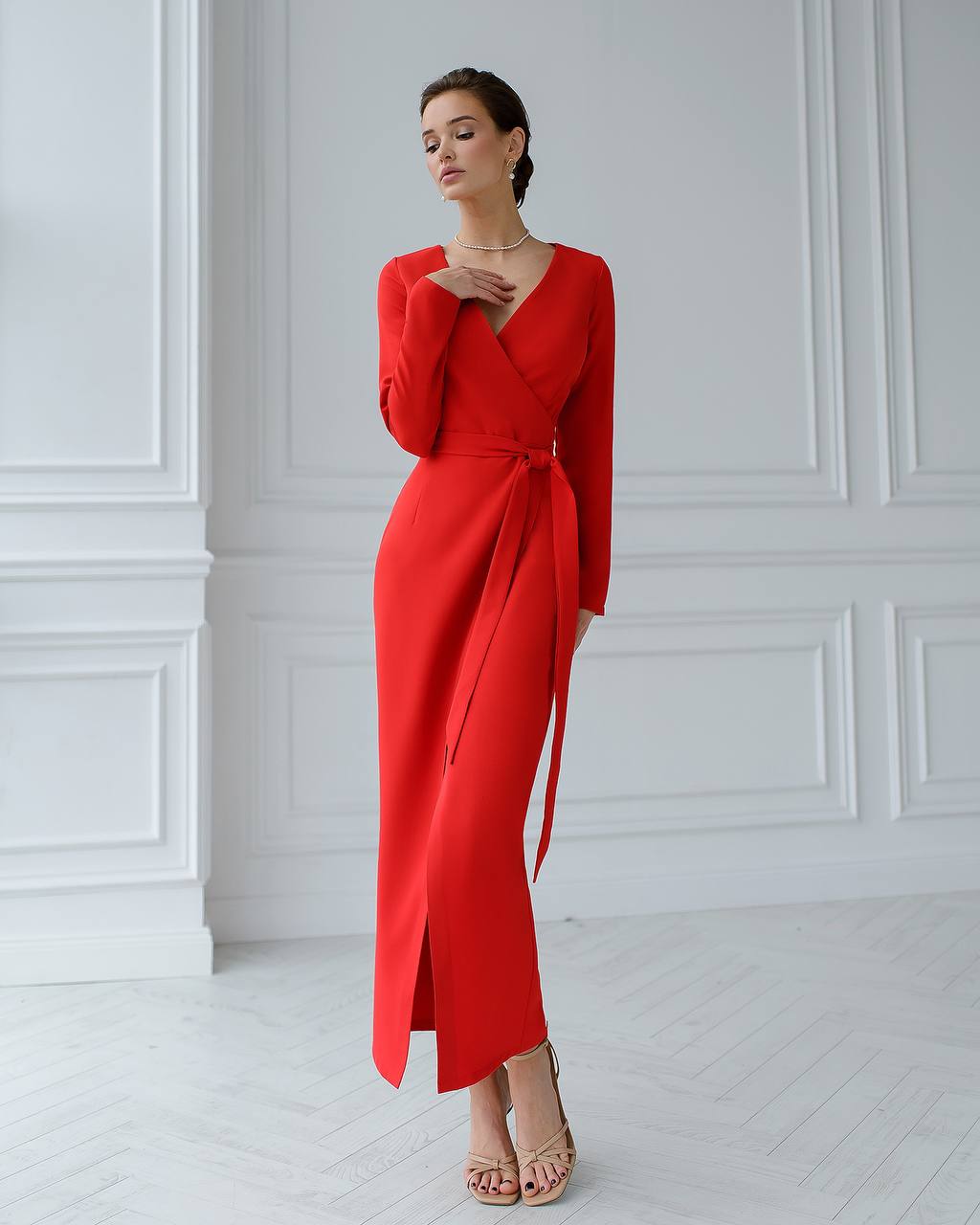 Woman wearing a red dress against a white wall