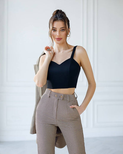 Woman wearing a black crop top and beige pants against a white background