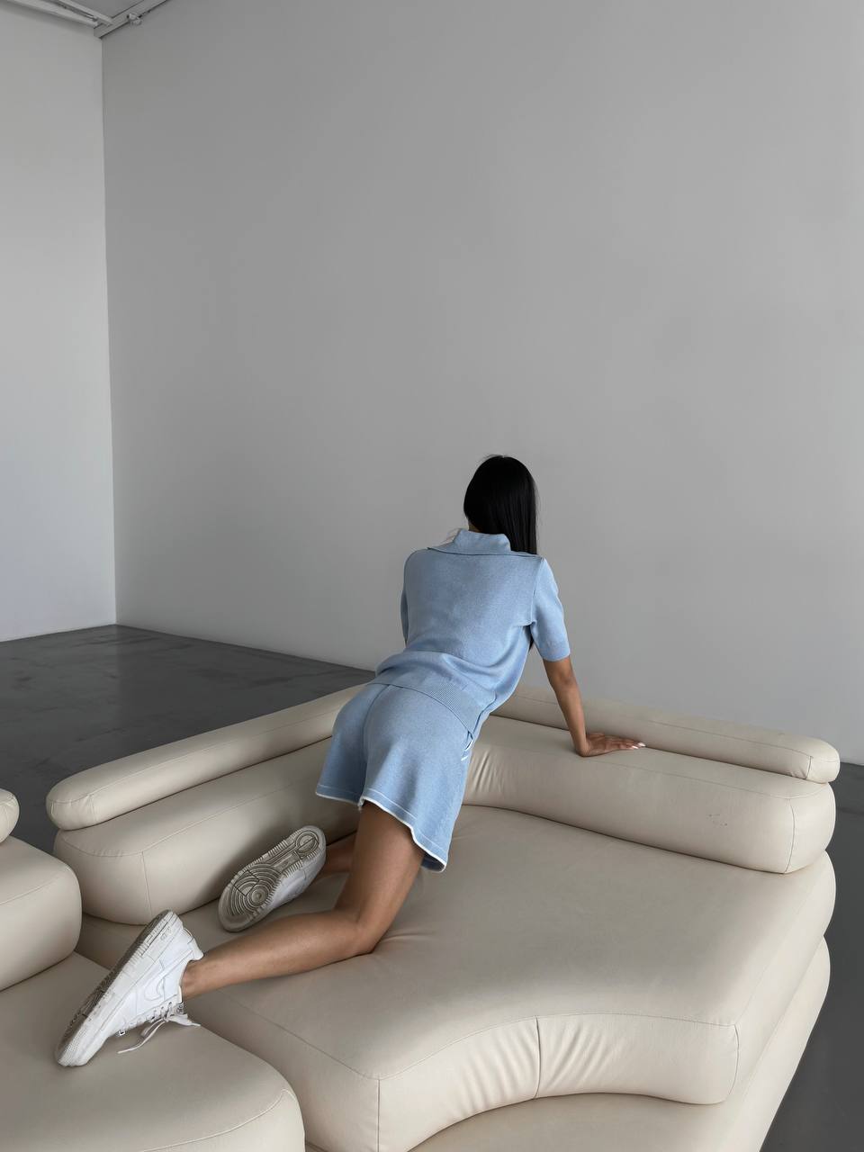 Person sitting on a modern beige sofa in a minimalistic room.