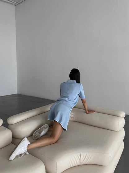 Person sitting on a modern beige sofa in a minimalistic room.