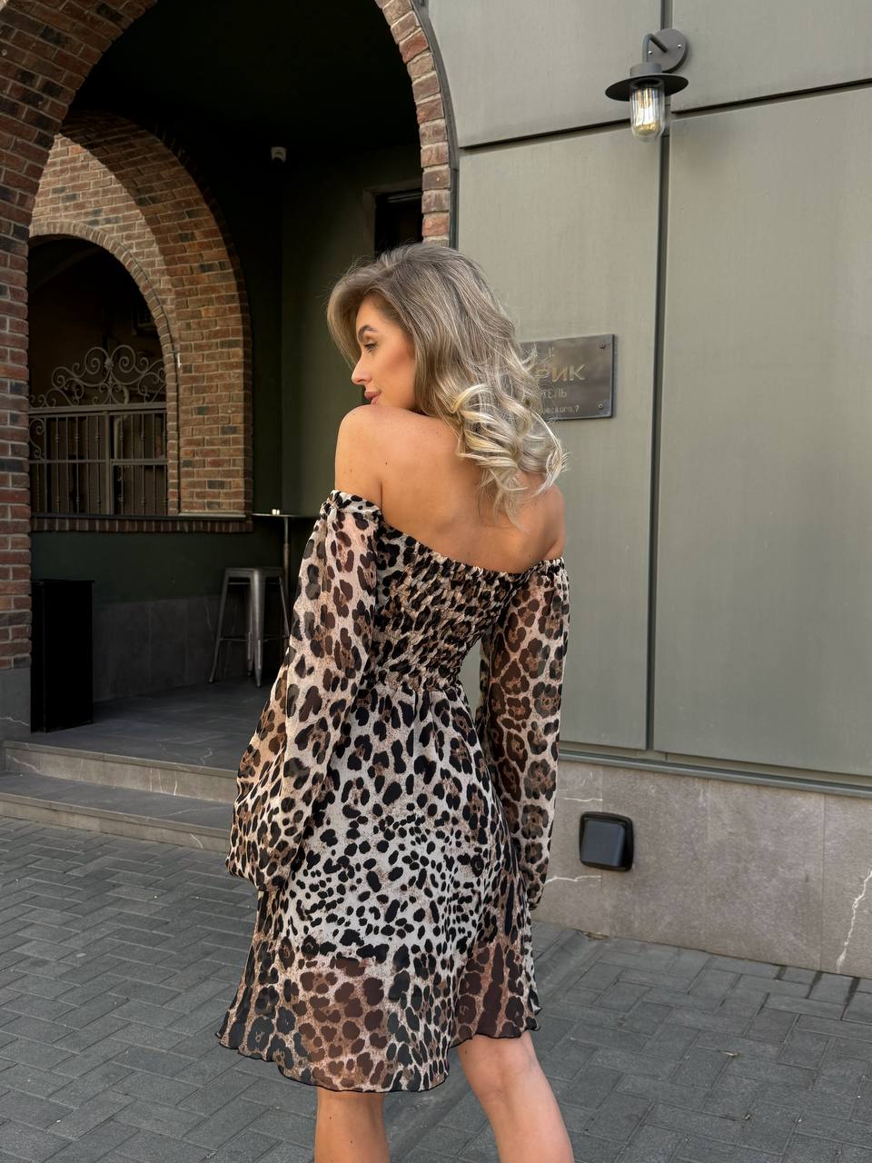 Woman wearing a leopard print dress walking outdoors.