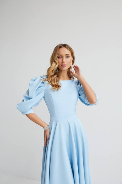 Woman wearing a light blue dress with puffed sleeves on a gray background