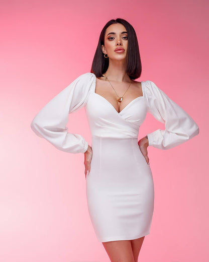 Woman wearing a white dress with long sleeves against a pink background