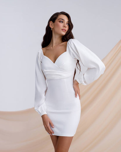 Woman wearing a white dress with long sleeves against a neutral background
