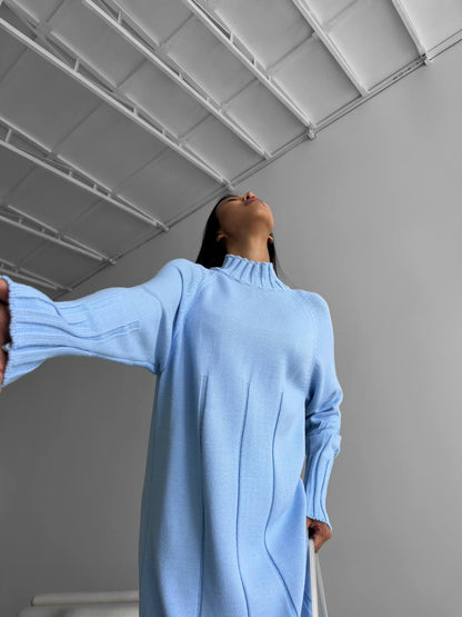 Person wearing a light blue sweater standing against a plain background