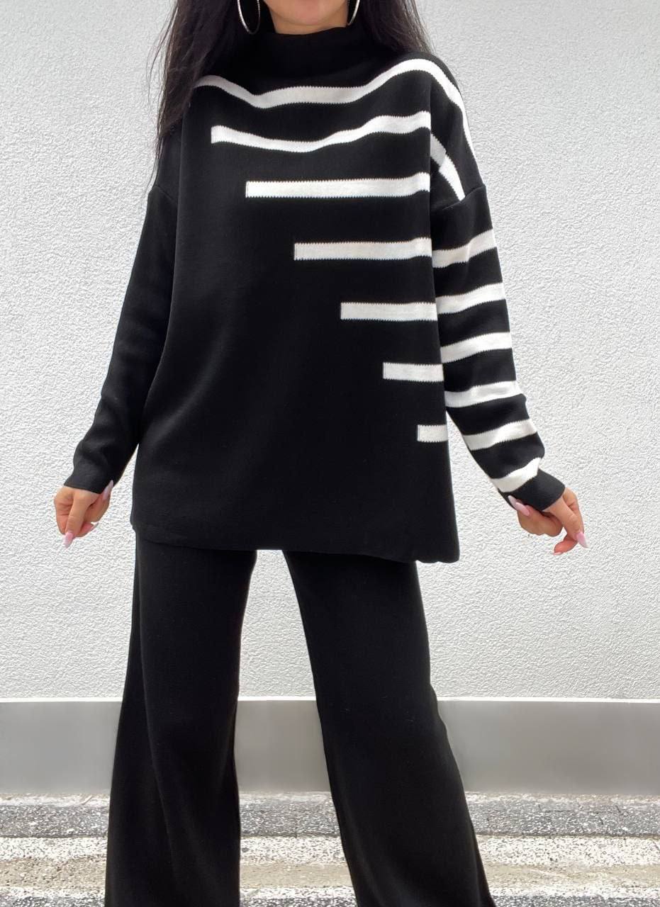 Person wearing a black and white striped sweater with wide-leg pants against a neutral background