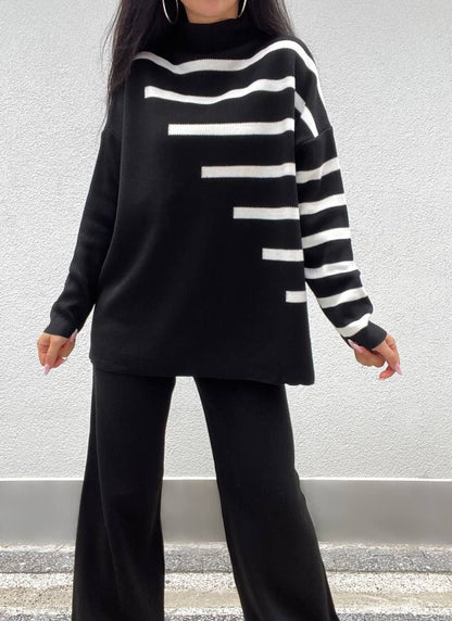 Person wearing a black and white striped sweater with wide-leg pants against a neutral background
