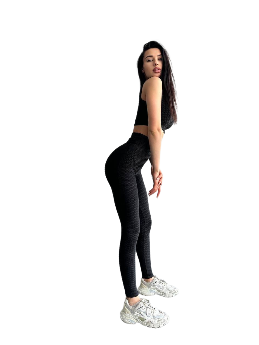Woman wearing black leggings and a black crop top on a white background