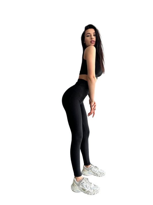 Woman wearing black leggings and a black crop top on a white background