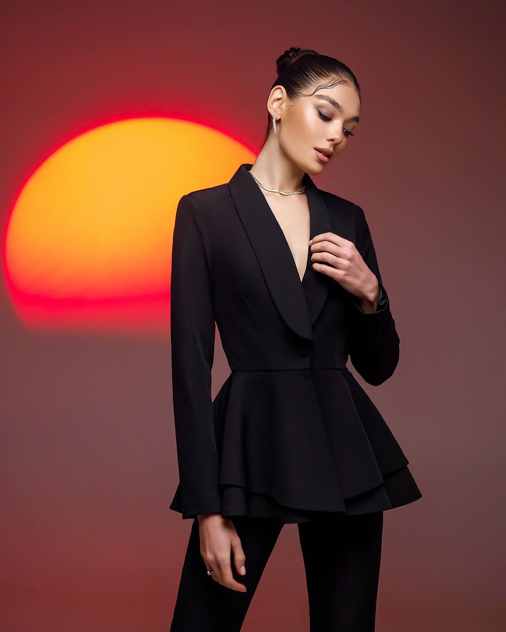 Woman in a black peplum suit with a sunset in the background