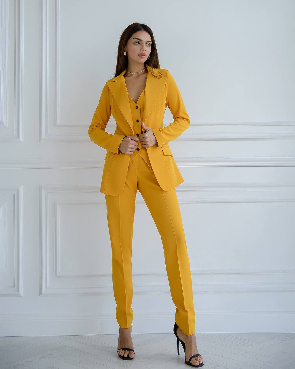 Woman wearing a yellow suit against a white wall