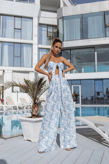 Woman in a blue floral dress standing on a rooftop with a pool and modern building in the background