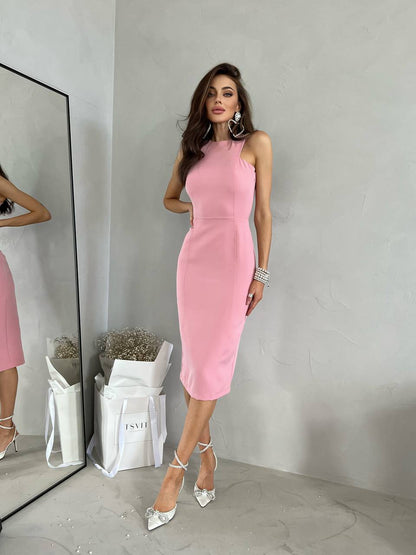 Woman in a pink dress standing in front of a mirror with a gray wall background
