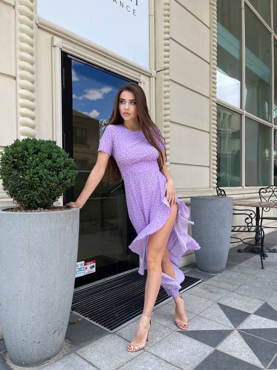 Woman in a purple dress standing outside a building