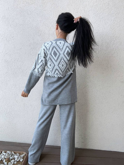 Person wearing a gray patterned outfit standing against a plain wall.