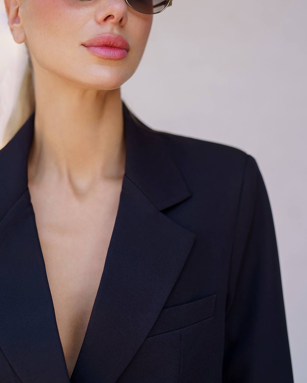 Person wearing a dark blue blazer against a neutral background